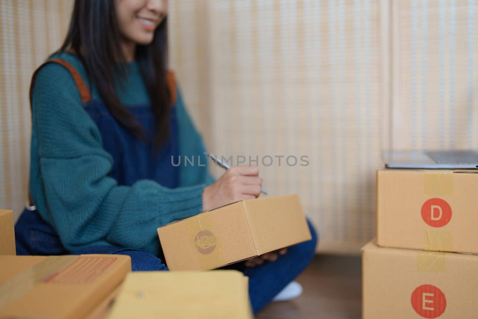 Starting small business entrepreneur of independent young Asian woman online seller is using computer and taking orders to pack products for delivery to customers. SME delivery concept by Manastrong