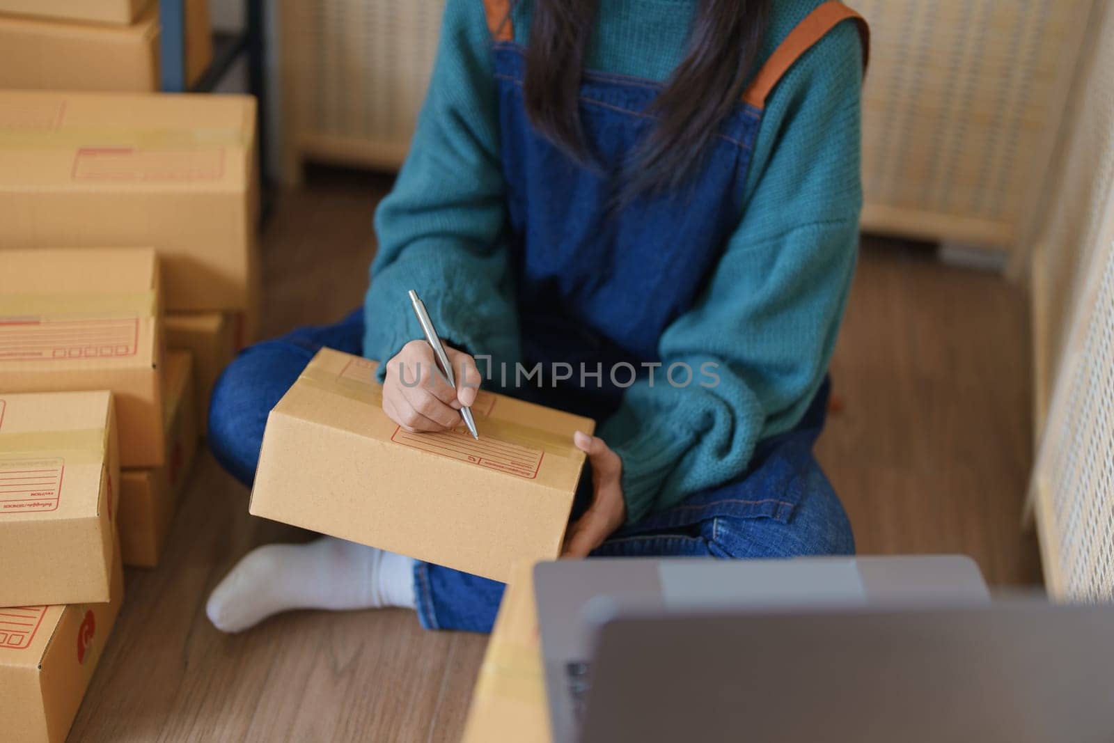 Starting small business entrepreneur of independent young Asian woman online seller is using computer and taking orders to pack products for delivery to customers. SME delivery concept by Manastrong