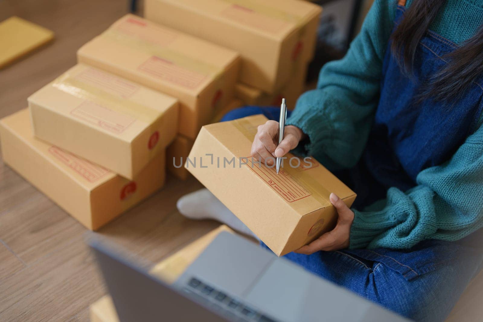 Starting small business entrepreneur of independent young Asian woman online seller is using computer and taking orders to pack products for delivery to customers. SME delivery concept by Manastrong