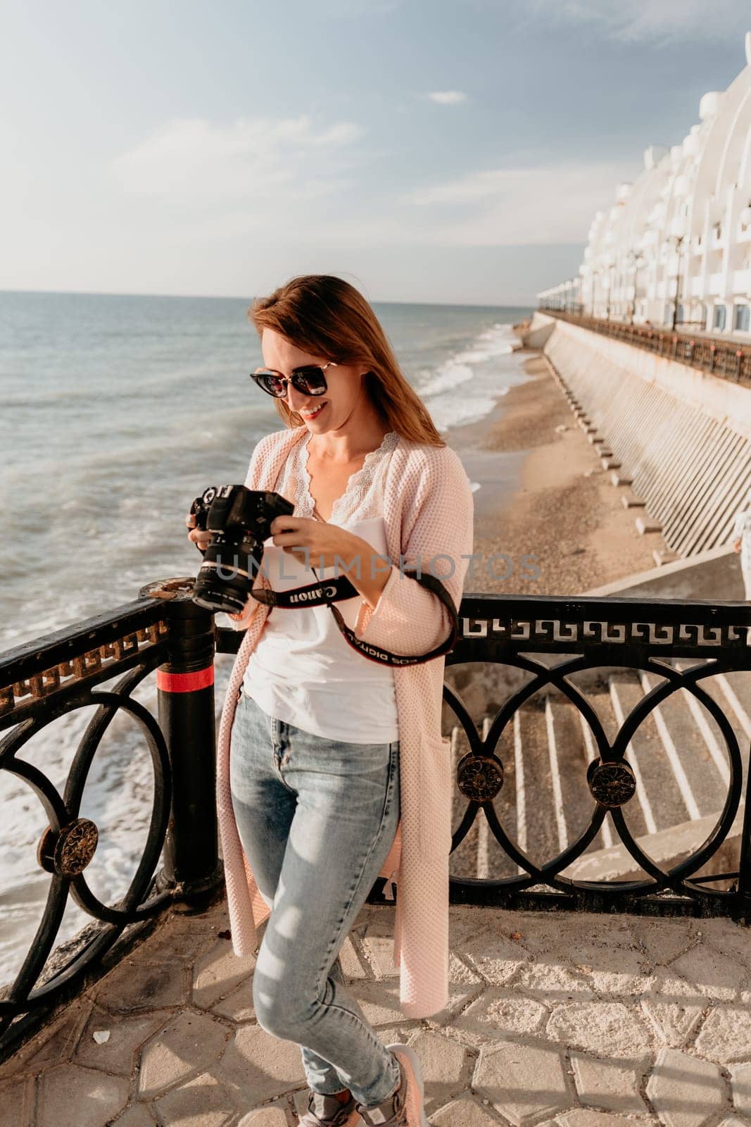 Woman summer travel sea. Happy tourist enjoy taking picture outdoors for memories. Carefree woman traveler posing on beach at sea on sunset, sharing travel adventure journey. Holiday vacation concept. by panophotograph