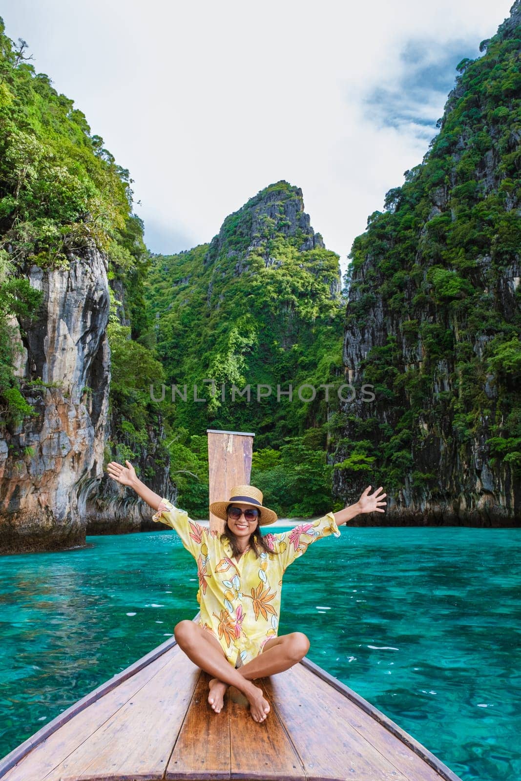 Happy Asian women in front of a longtail boat with hands up at Kho Phi Phi Thailand by fokkebok