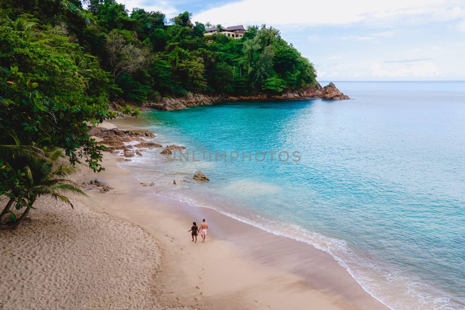 A couple of men and women are relaxing on a white tropical beach with palm trees in Phuket Thailand. Banana Beach Phuket on a sunny day