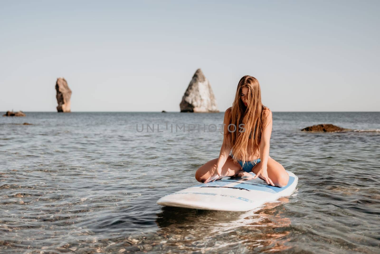 Close up shot of happy young caucasian woman looking at camera and smiling. Cute woman portrait in bikini posing on a volcanic rock high above the sea