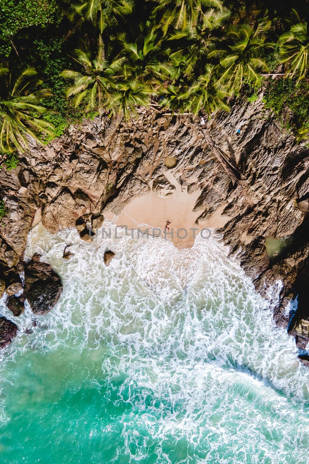 A couple of men and women relaxing on a white tropical beach with palm trees in Phuket Thailand by fokkebok