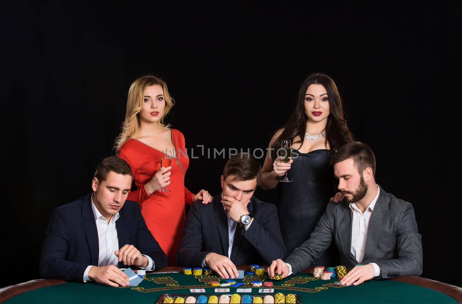 People at the poker table in casino. Men in suits, the women in beautiful dresses. Vacation with friends