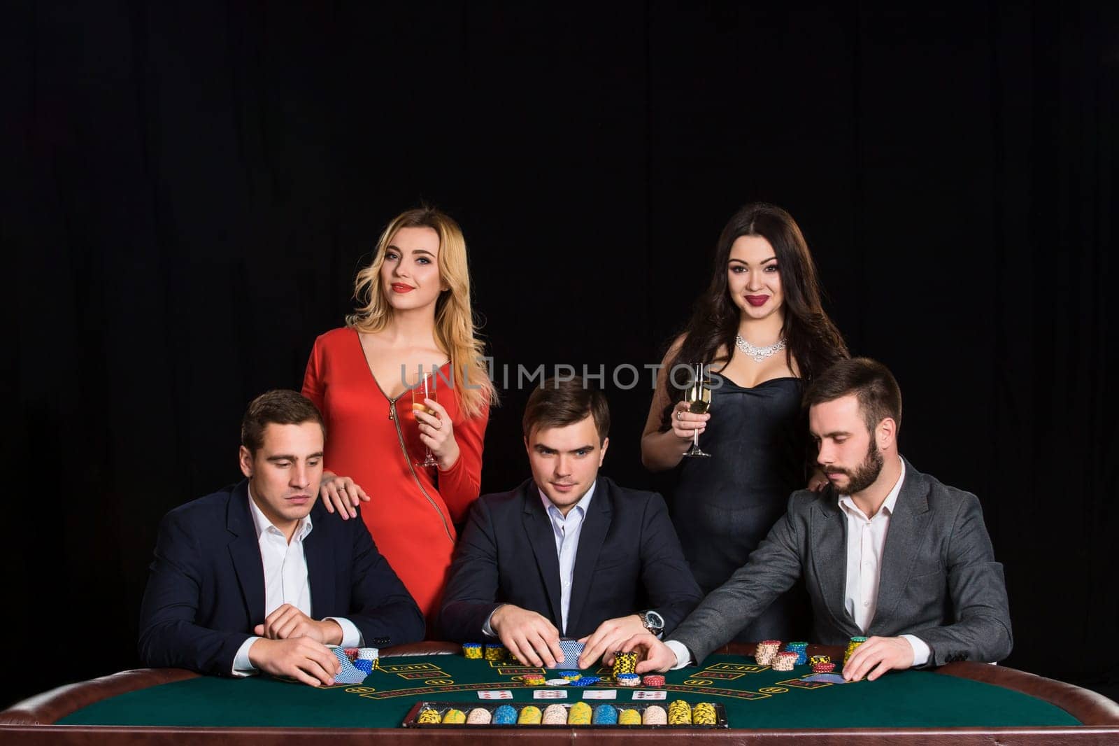 People at the poker table in casino. Men in suits, the women in beautiful dresses. Vacation with friends