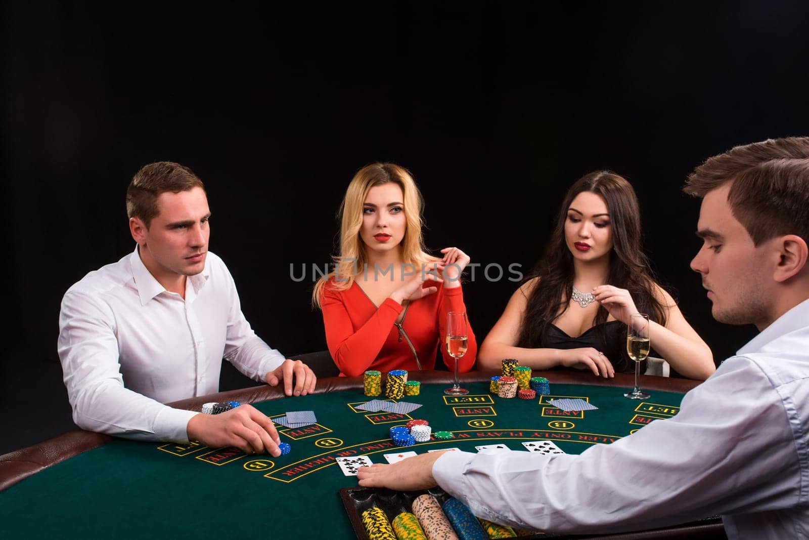 Friends enjoying a gambling night. Young people sit at the game table. The dealer deals the cards