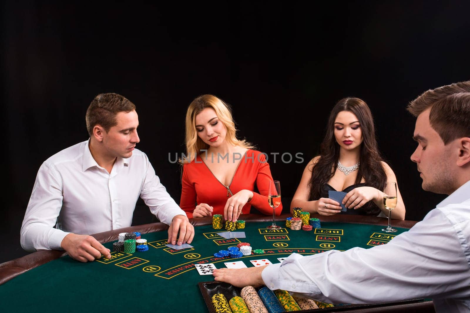 Friends enjoying a gambling night. Young people sit at the game table. The dealer deals the cards