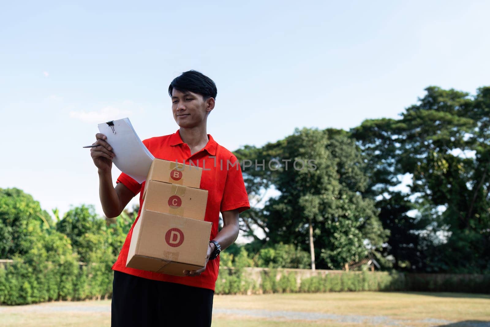 Young delivery man checking detail about parcel. Male postman courier with shopping package. Shipment concept.