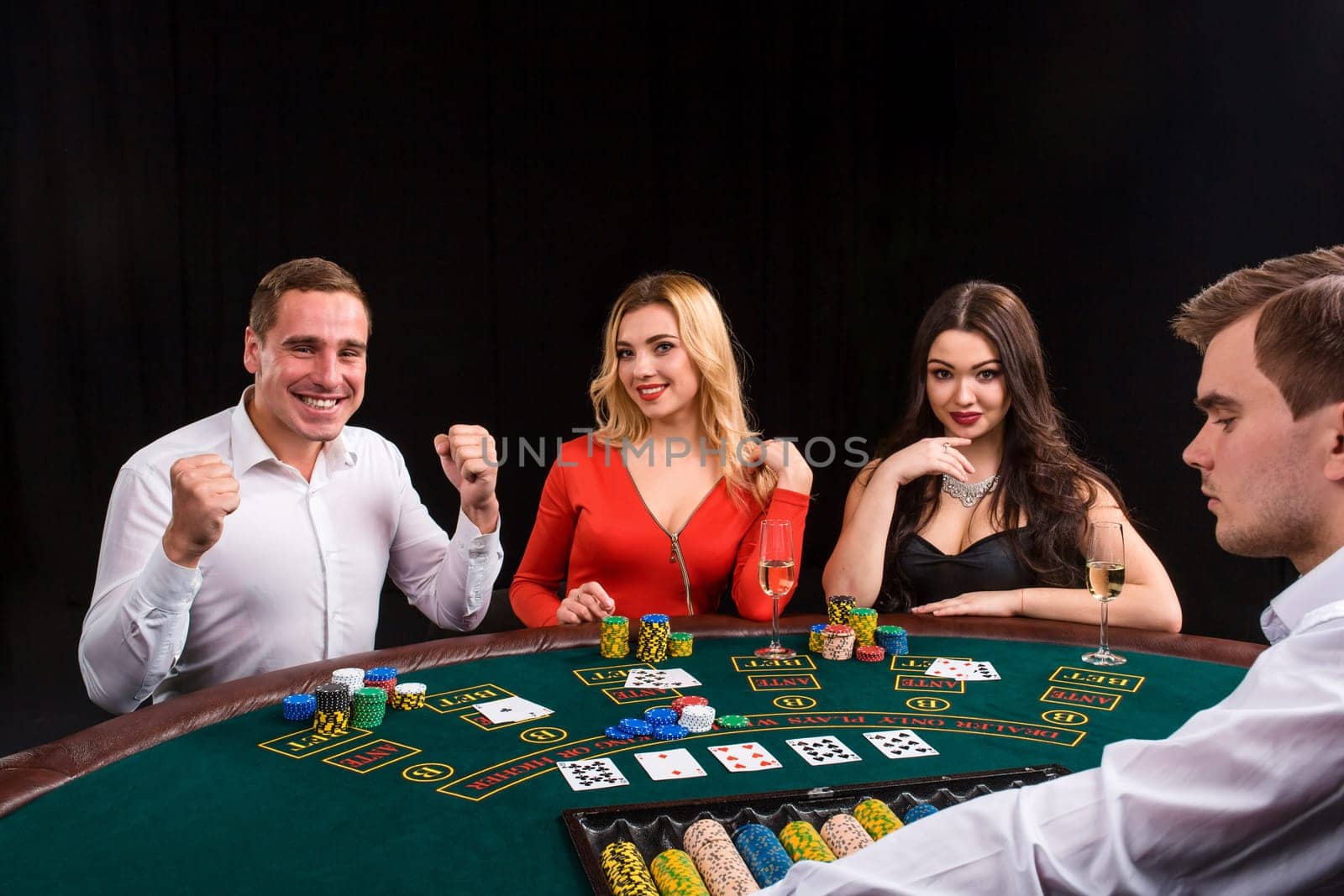 Friends enjoying a gambling night. Young people sit at the game table. The dealer deals the cards