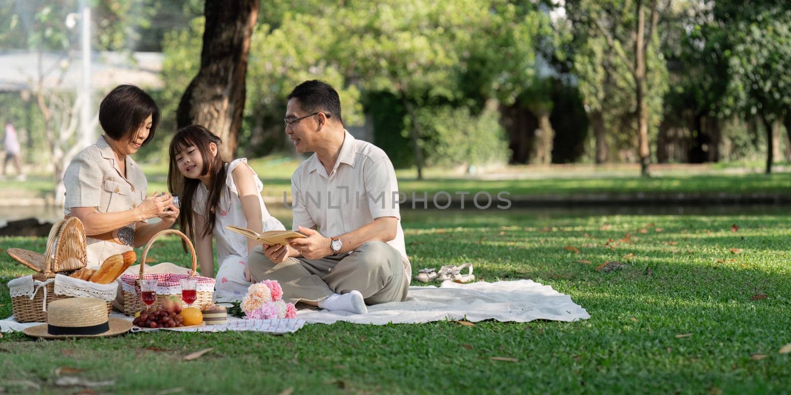 happy smiling family grandparent and grandchild picnic together outside at park by itchaznong