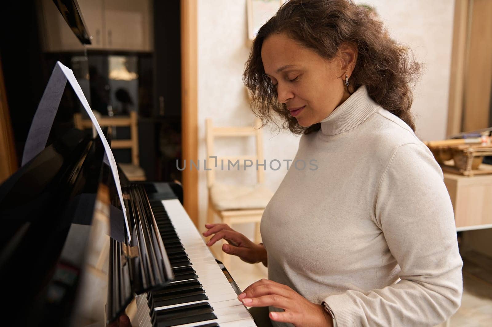 Authentic portrait of young adult woman performing melody on piano forte. Confident female musician playing grand piano by artgf