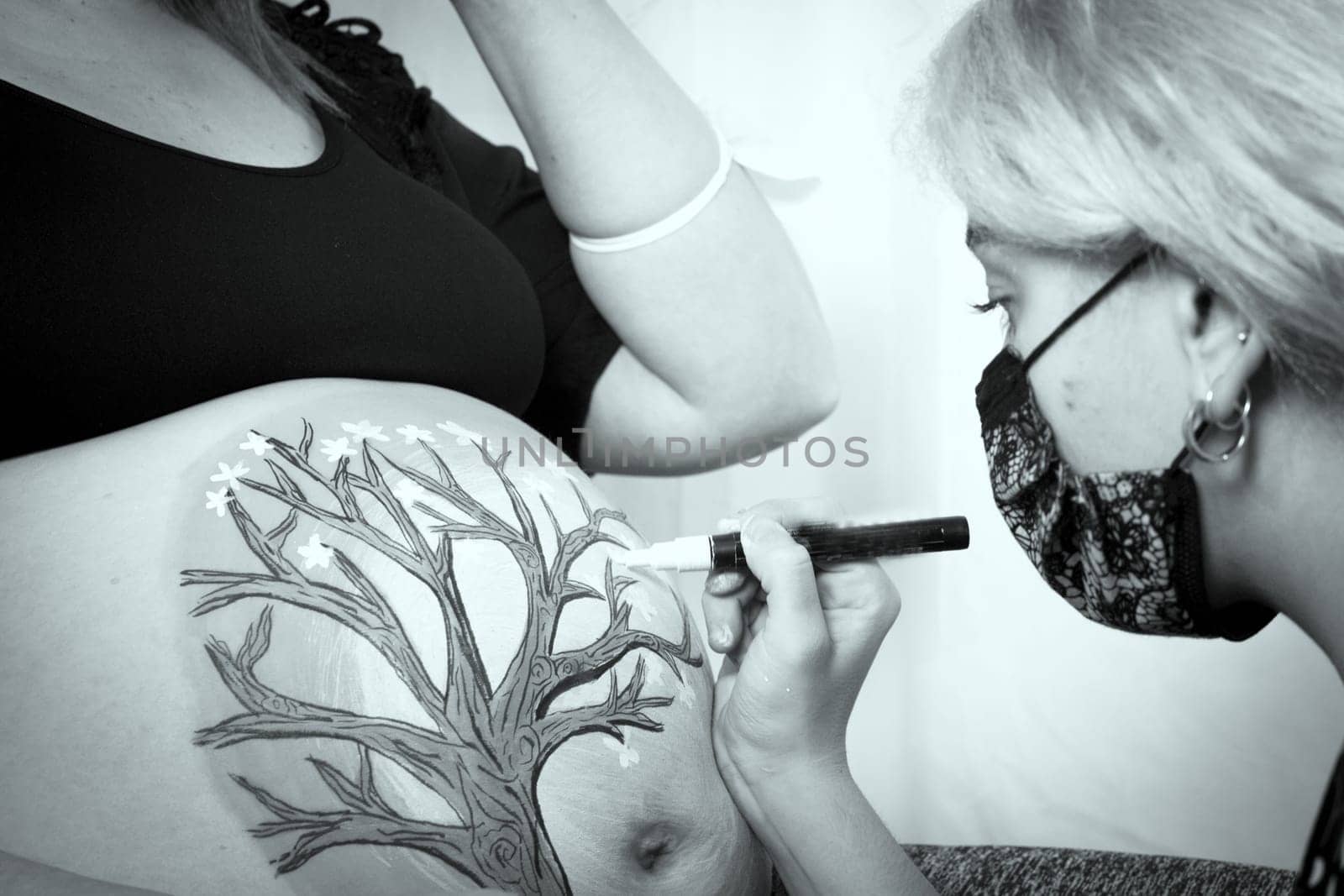 Girl drawing on belly of pregnant woman. No copy space