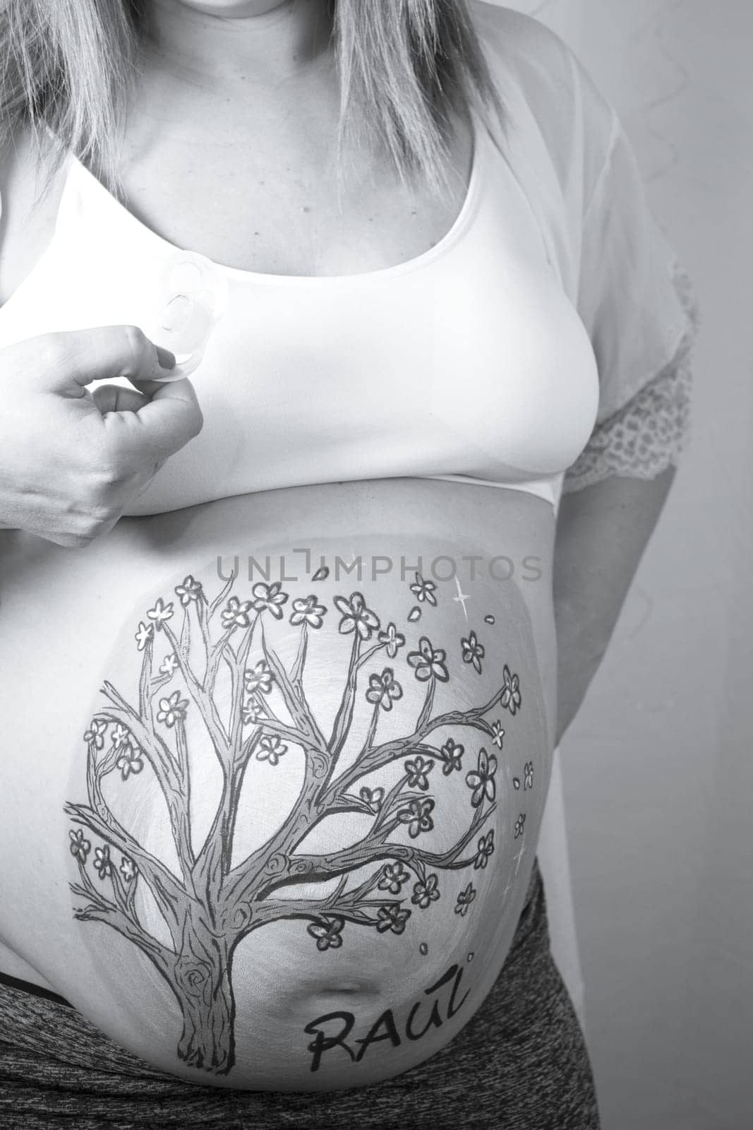 Eight month pregnant woman holding a pacifier in orange color