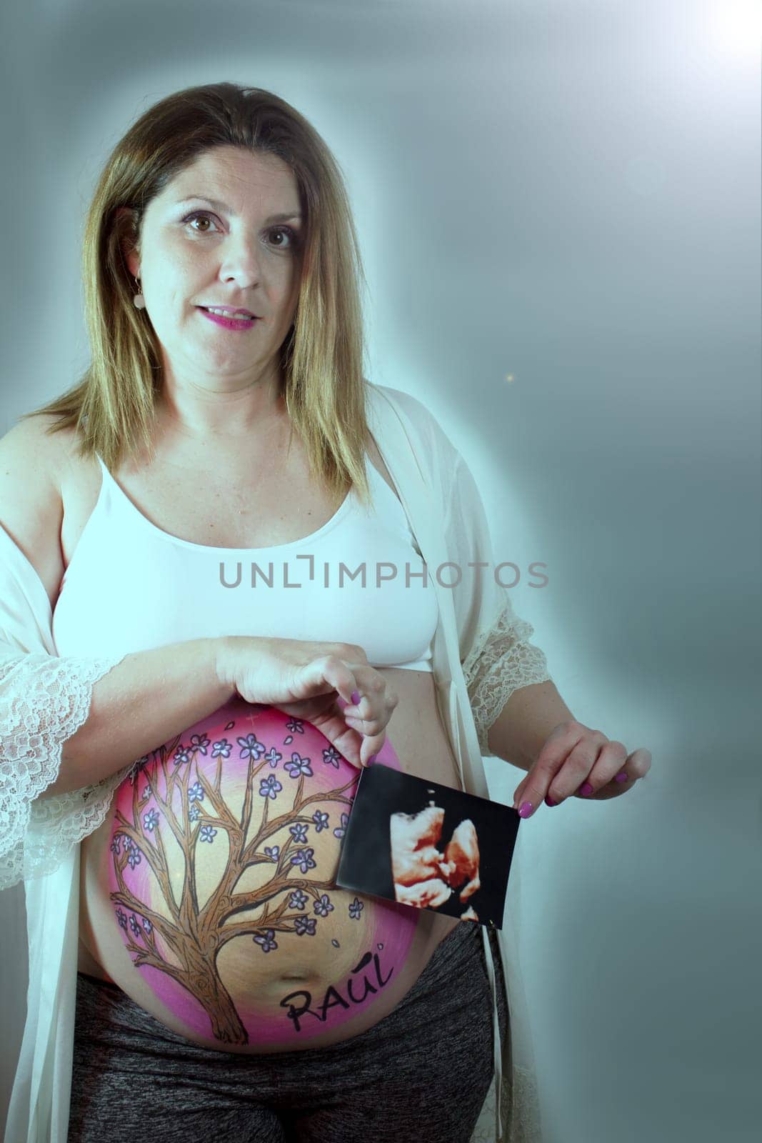 Eight month pregnant woman holding ultrasound scan of baby. No copy space