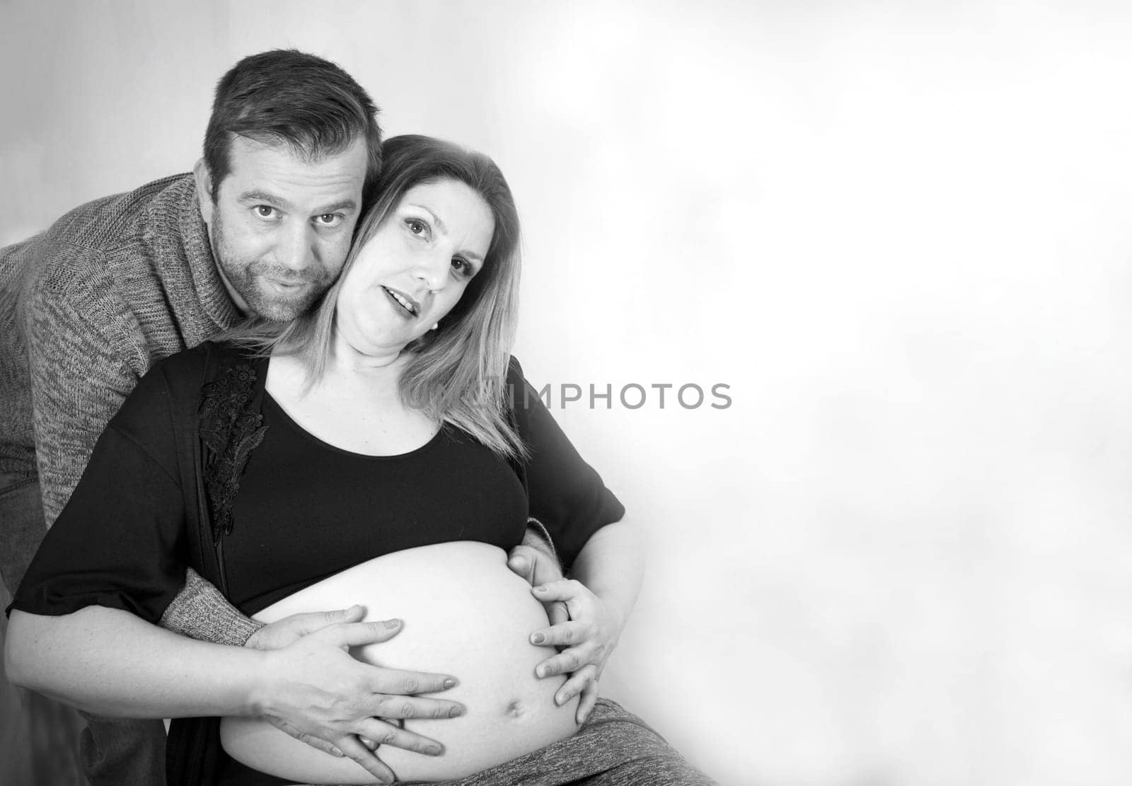 Eight months pregnant woman and dad hugging her. Happy expression