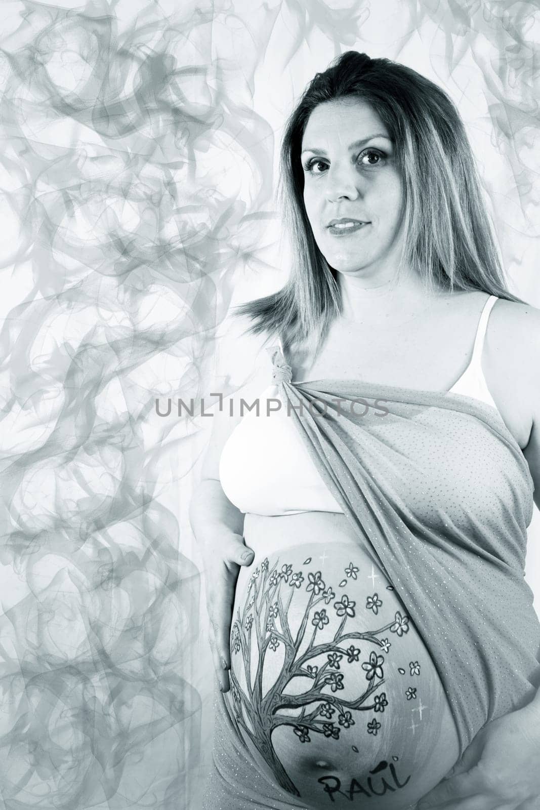 Eight months pregnant woman with bright dress and drawing on her belly. No copy space