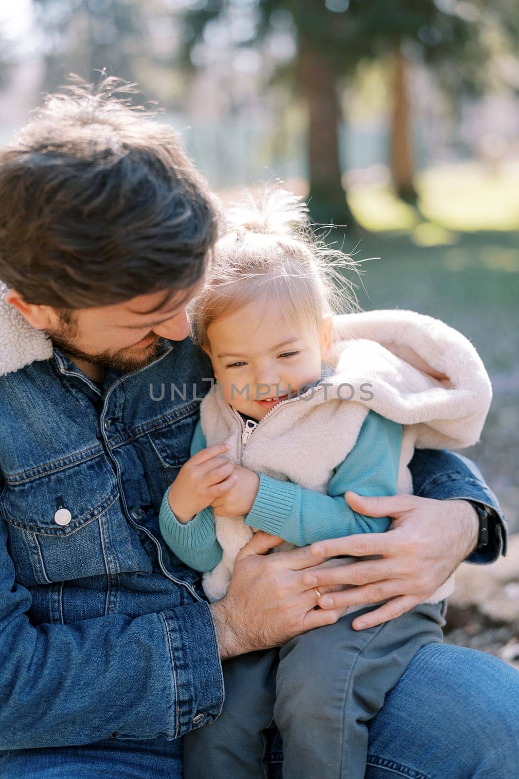 Dad looks at a little girl on his knees hugging her. High quality photo