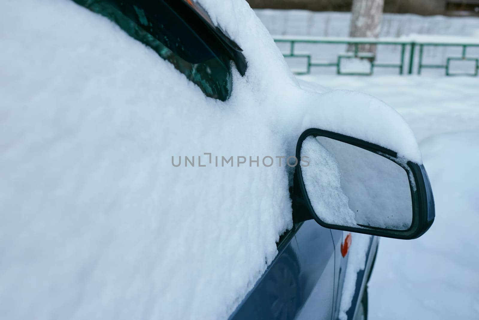 snow-covered car in winter and a front view mirror by electrovenik