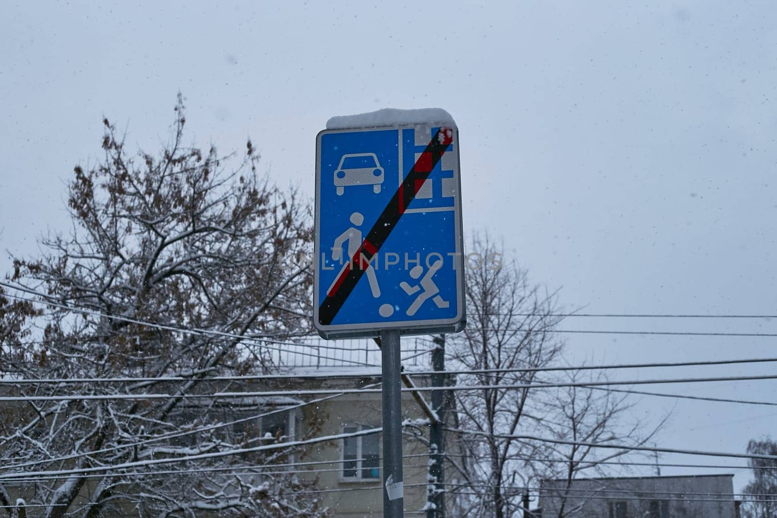 Photo a blue traffic sign in winter on the background of a multi-storey building.