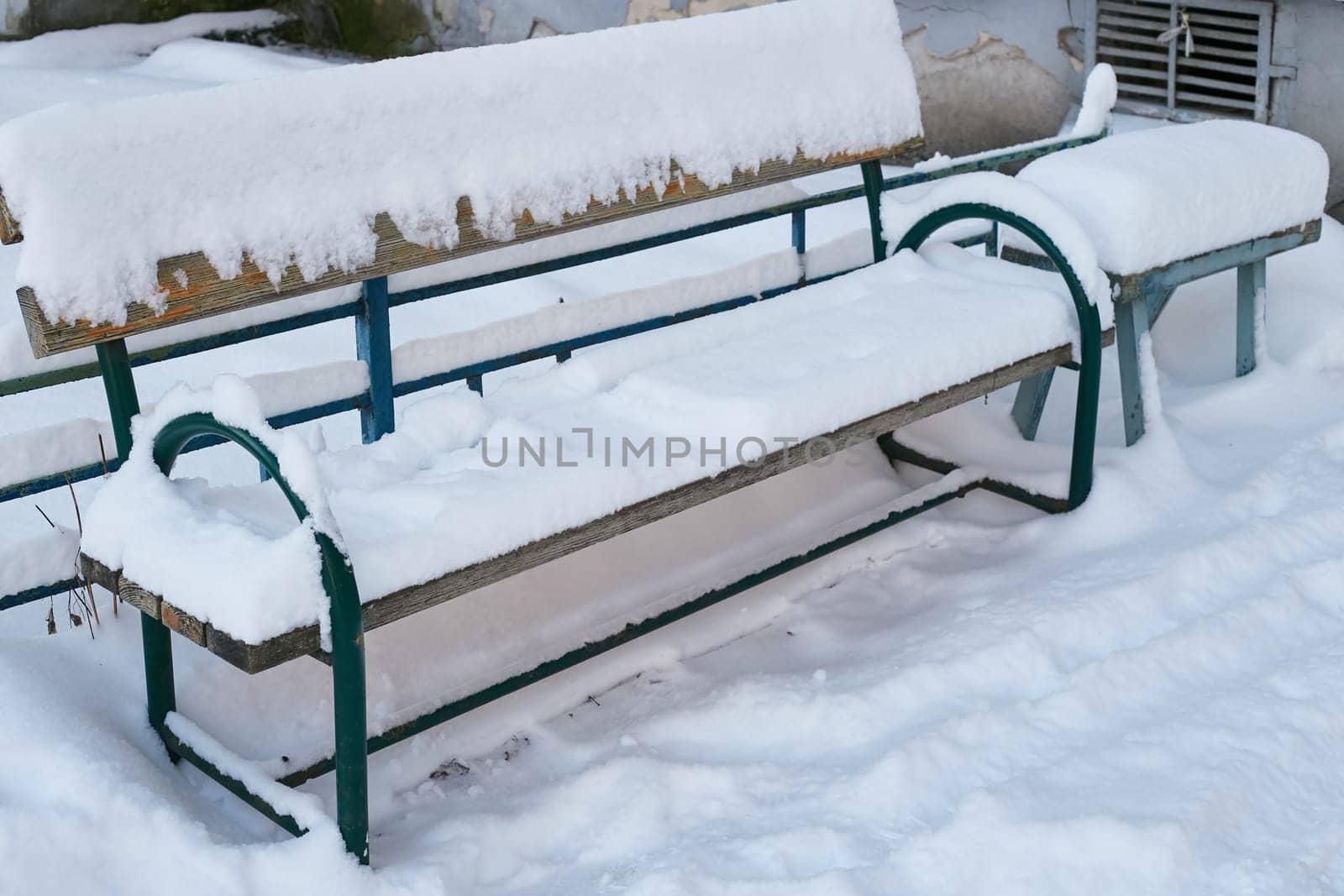 wooden bench snow next to an apartment building. by electrovenik