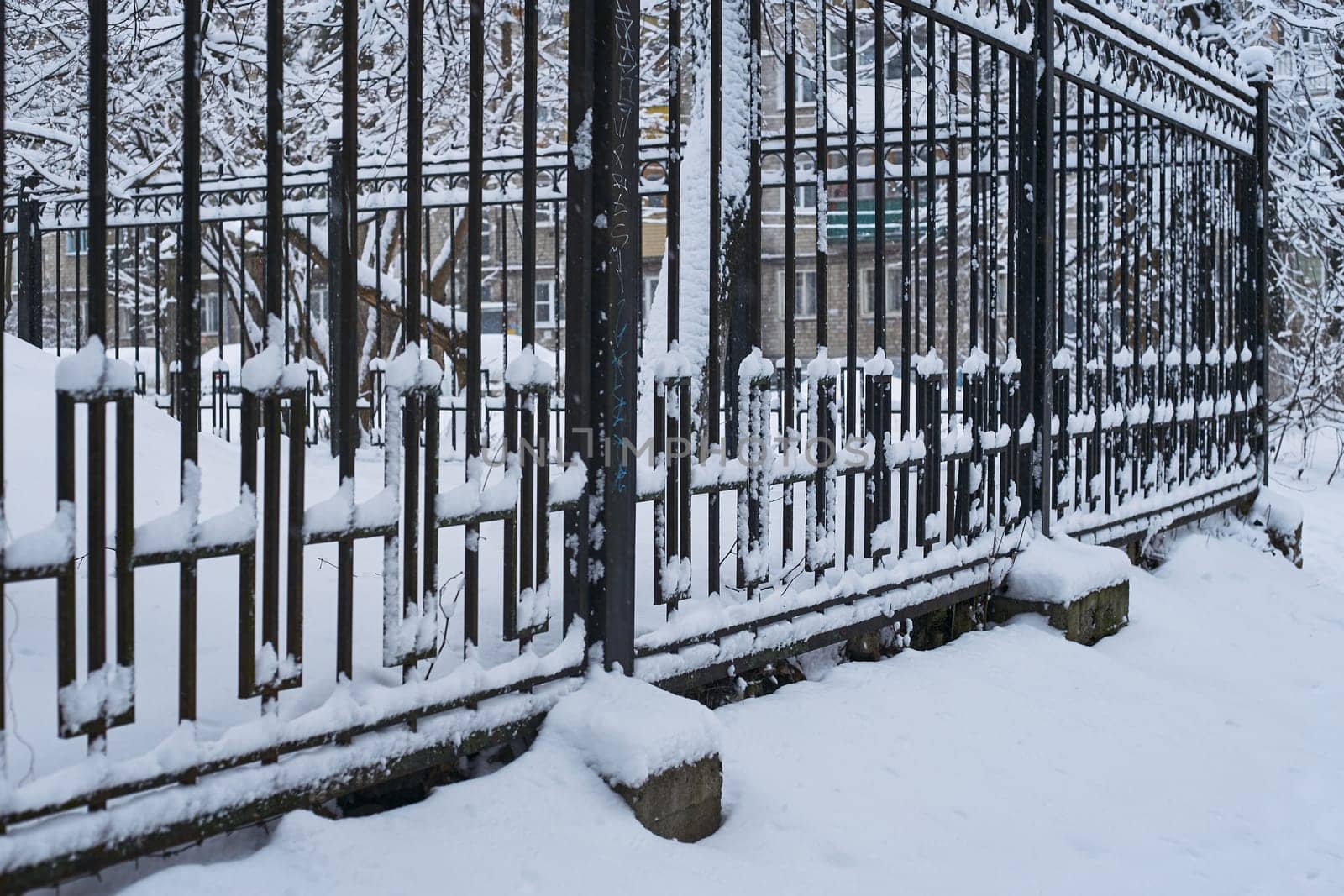 Photo a metal fence is a high black fence. Forged gate fence. In winter, in snow and snowdrifts.