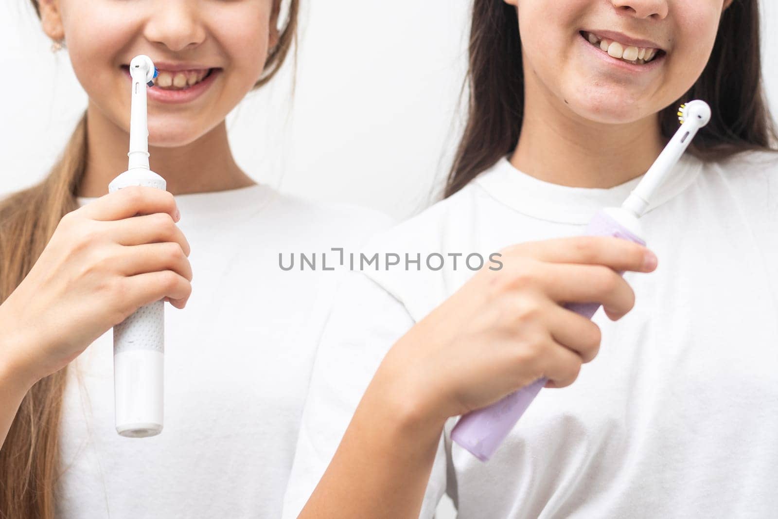 Portrait of two beautiful girls kids with perfect smile holding toothbrushes. Child dental care, oral hygiene concept by Andelov13