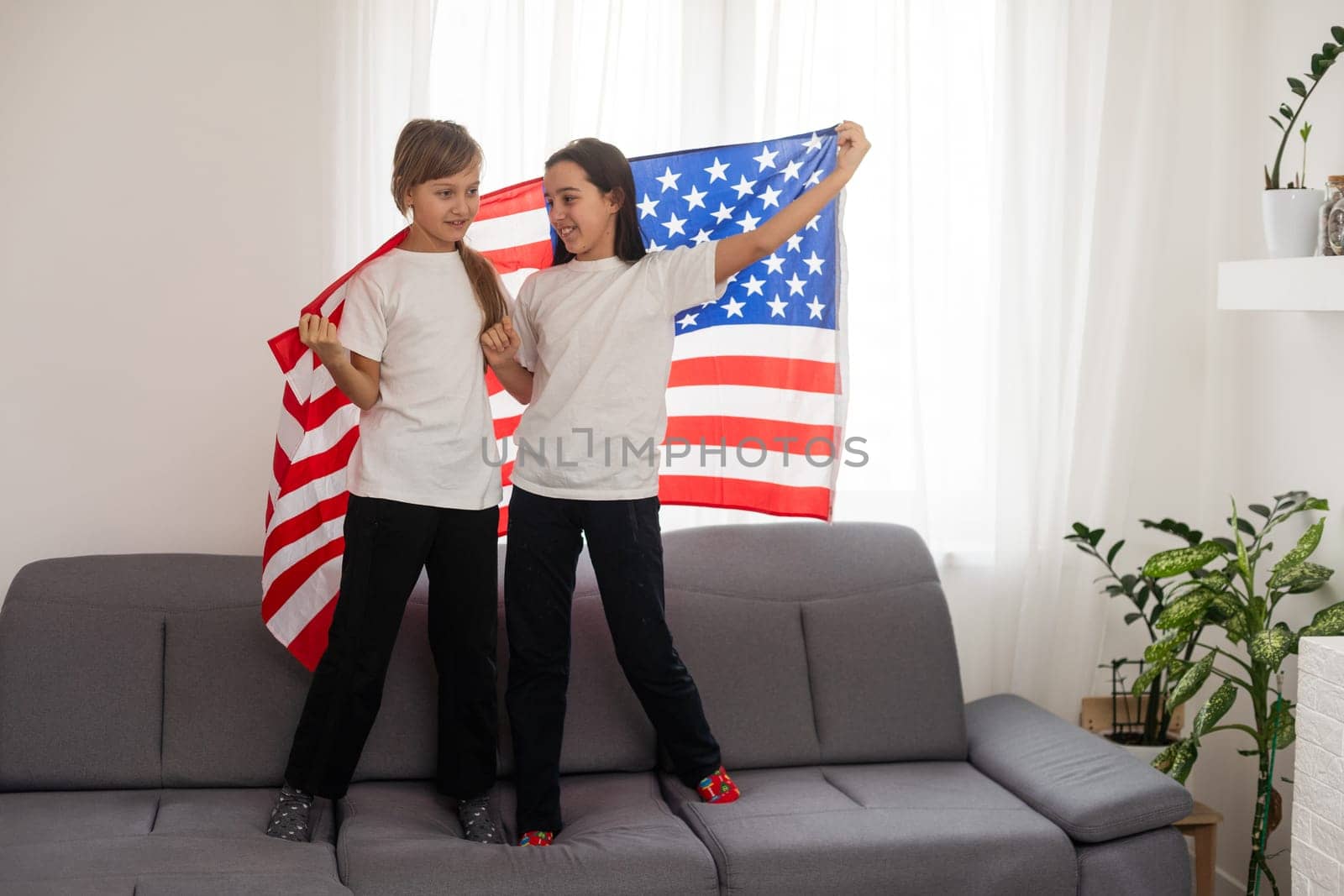 cheerful adorable kids standing under american flag and looking at camera by Andelov13
