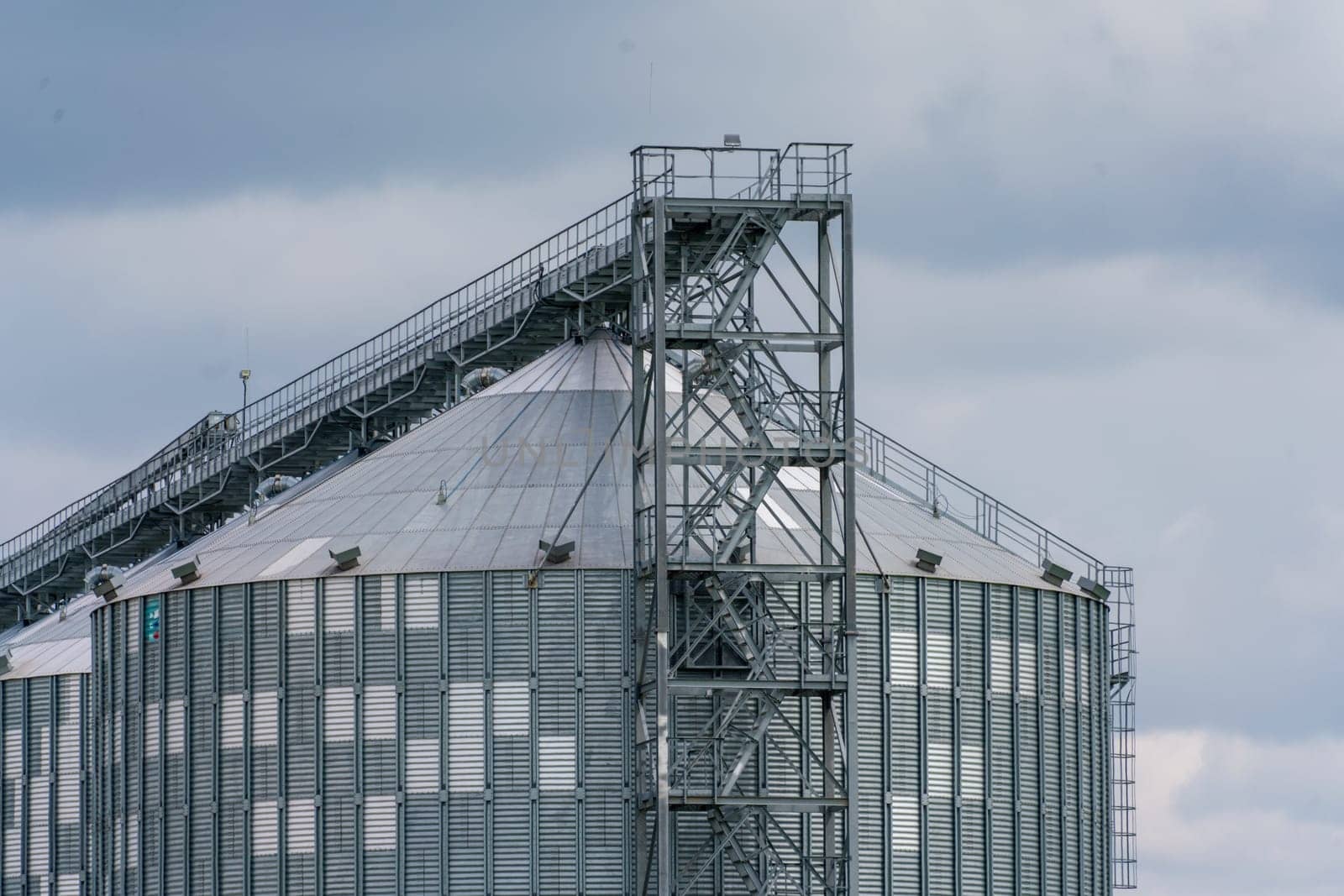 Granary elevator, silver silos on agro manufacturing plant for processing drying cleaning and storage of agricultural products, flour, cereals and grain. Large iron barrels of grain