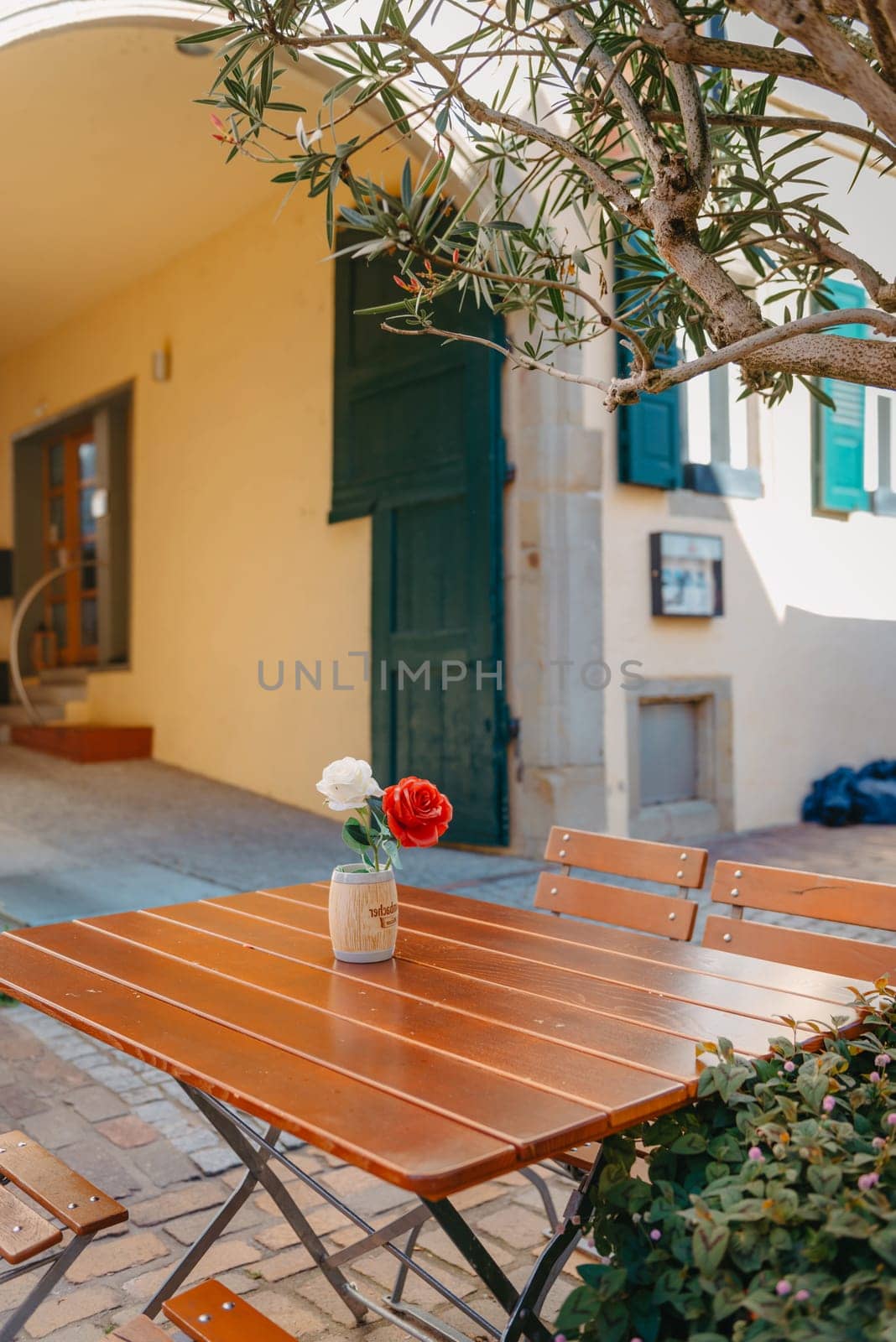 Empty cafe terrace with white table and chair. exterior of the cafe restaurant. interior Street cafe. Cozy street with flowers and French-style cafe table. Decor facade of coffeehouse with bike. Table on a summer terrace with cake and teapot. Garden table and chairs