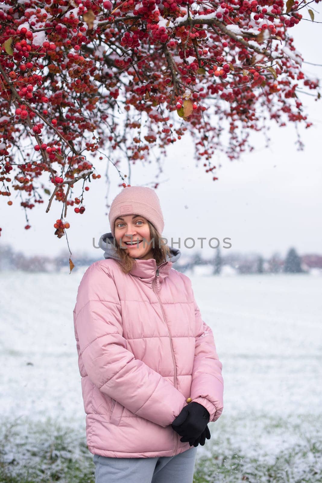 Winter Elegance: Portrait of a Beautiful Girl in a Snowy European Village. Winter lifestyle portrait of cheerful pretty girl. Smiling and having fun in the snow park. Snowflakes falling down. Christmas Radiance: Capturing Winter Elegance in the Snowy Ambiance of a European Village by Andrii_Ko