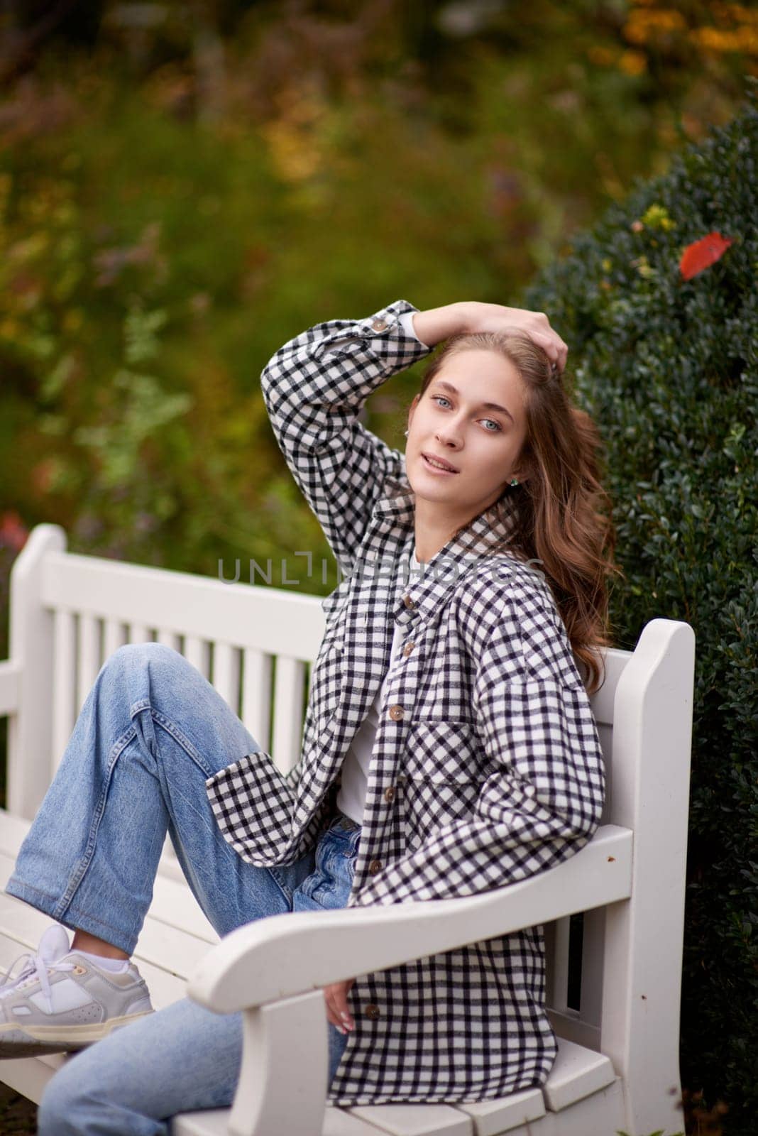 Beautiful teen blonde girl sits on a bench in an autumn park . attractive young smiling girl sitting on a bench in an autumn park by Andrii_Ko