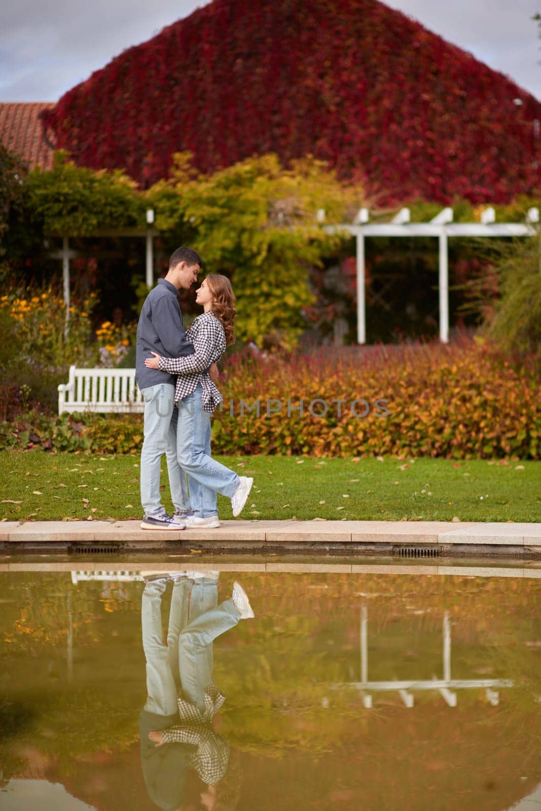 A couple in love hugs on the shore of a city pond in the European town. love story against the backdrop of autumn nature. romantic ambiance, couple goals, outdoor romance, seasonal charm, love in the city, autumnal vibes, European town, city pond, affectionate bonding, love story