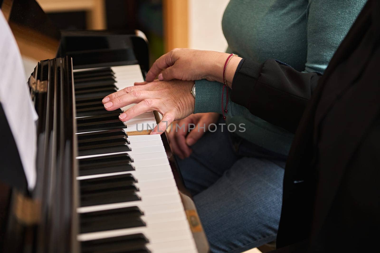 Close-up two women musicians pianists playing the piano in four hands, studying a new musical composition. Music lesson by artgf