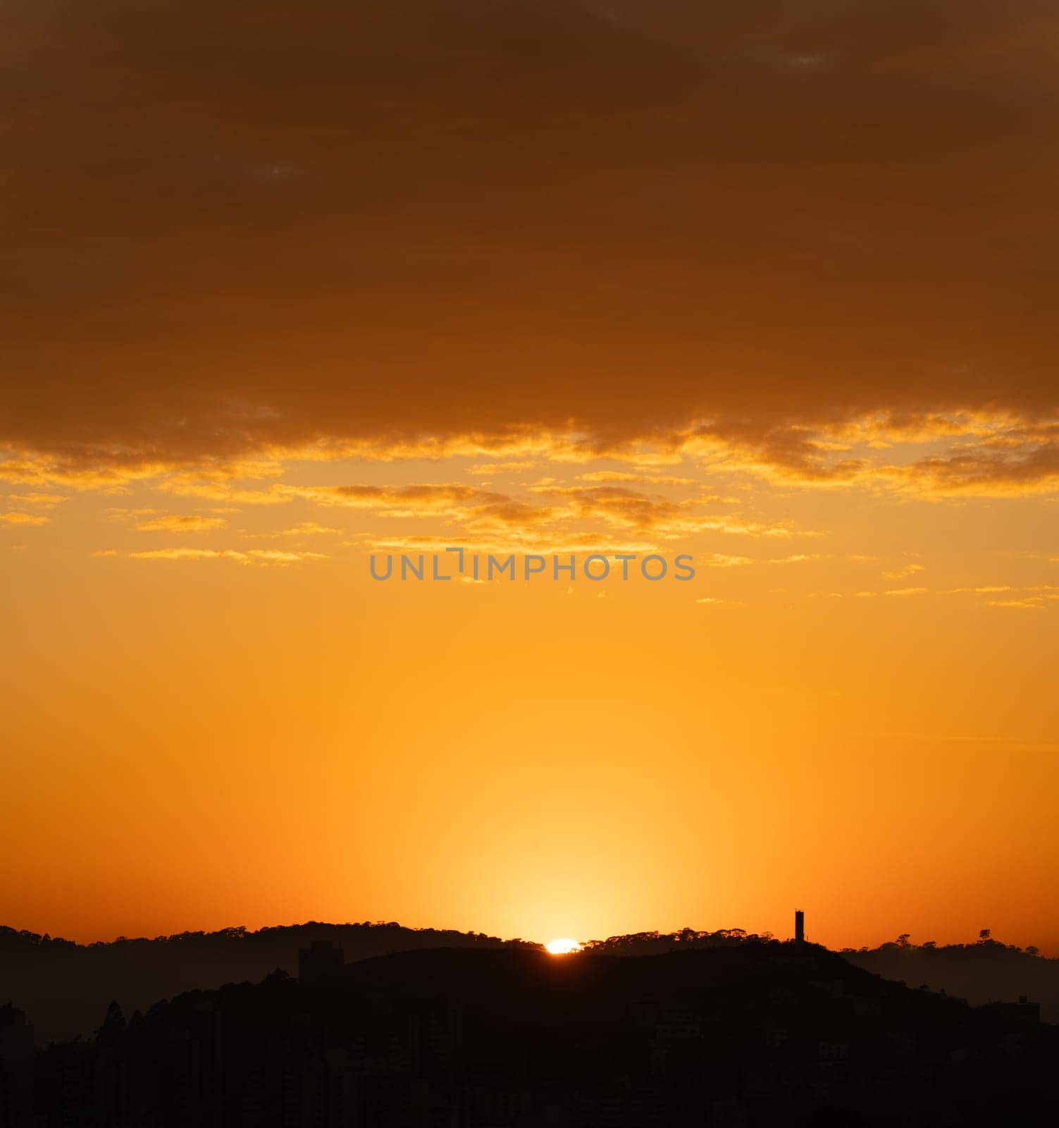 Dramatic sunrise over mountain silhouette and tower against orange sky, ideal for backgrounds or text space