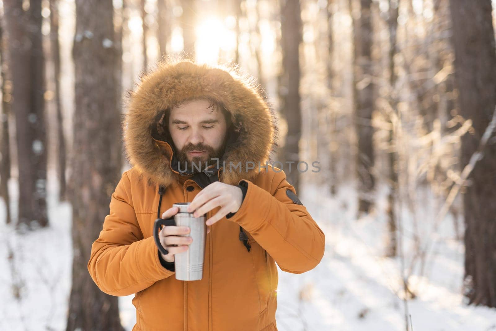 Close-up portrait handsome bearded millennial man in winter clothes and with thermos snow outdoor. Cold season and hot beverage in winter time, Copy space by Satura86