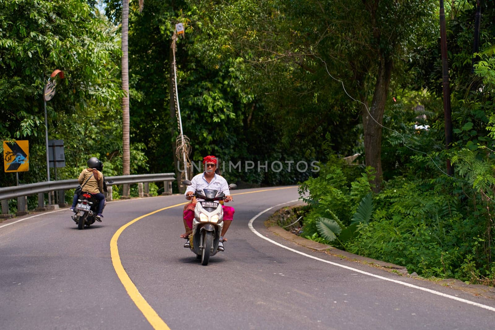 A person on a motorcycle rides a scenic asphalt road in Asia. Bali, Indonesia - 12.10.2022