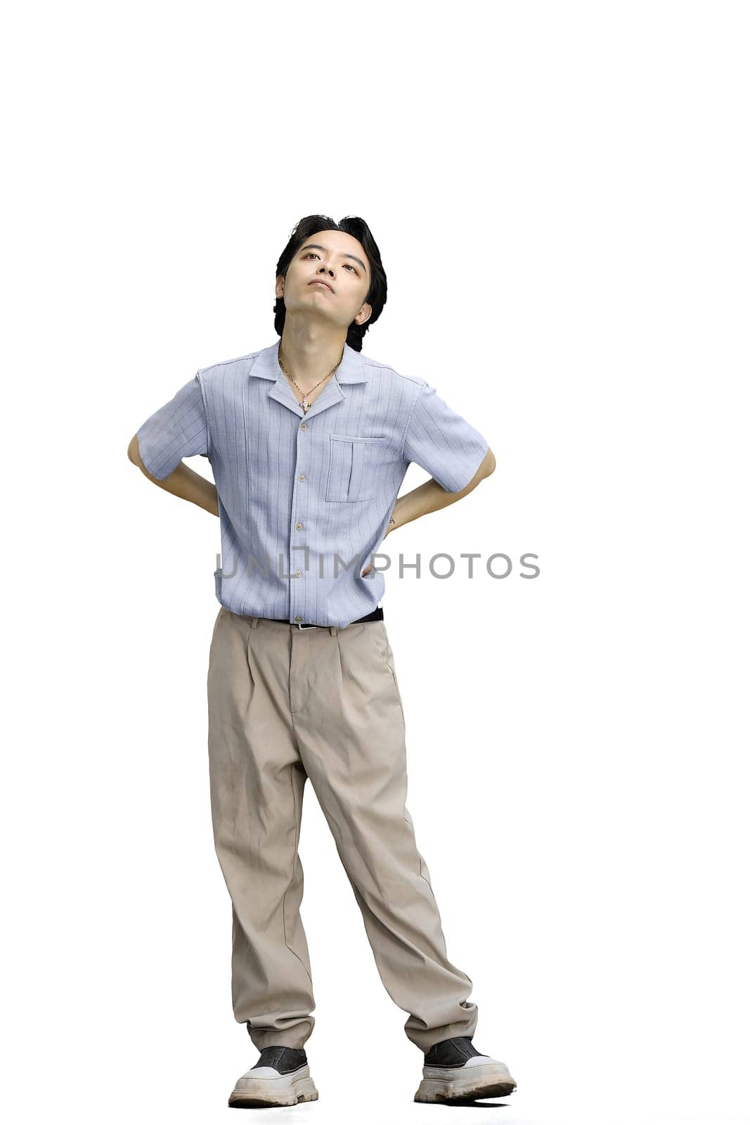 A guy in a blue shirt, on a white background, full-length, hands on his belt.