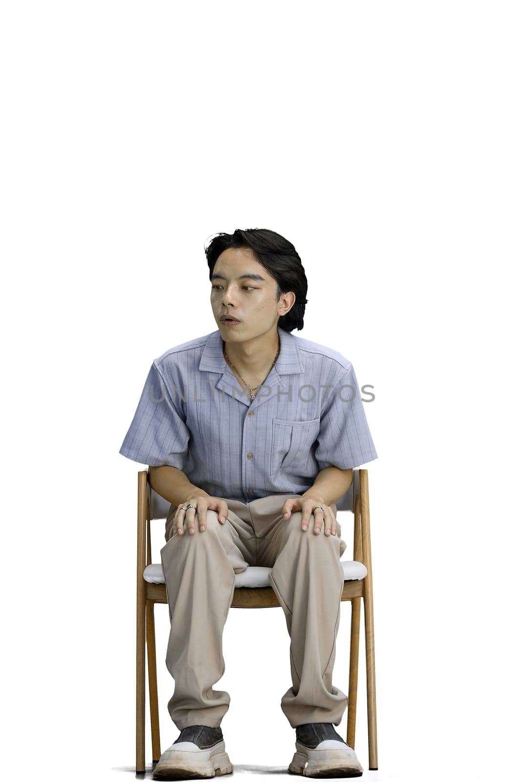 A guy in a blue shirt, on a white background, is sitting on a chair by Prosto