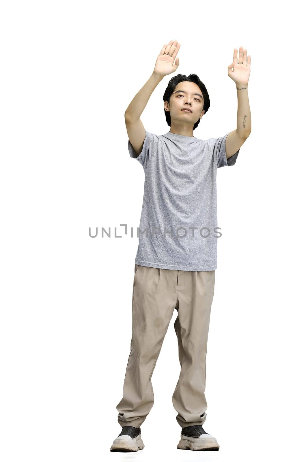 A guy in a gray T-shirt, on a white background, in full height, raised his hands up.