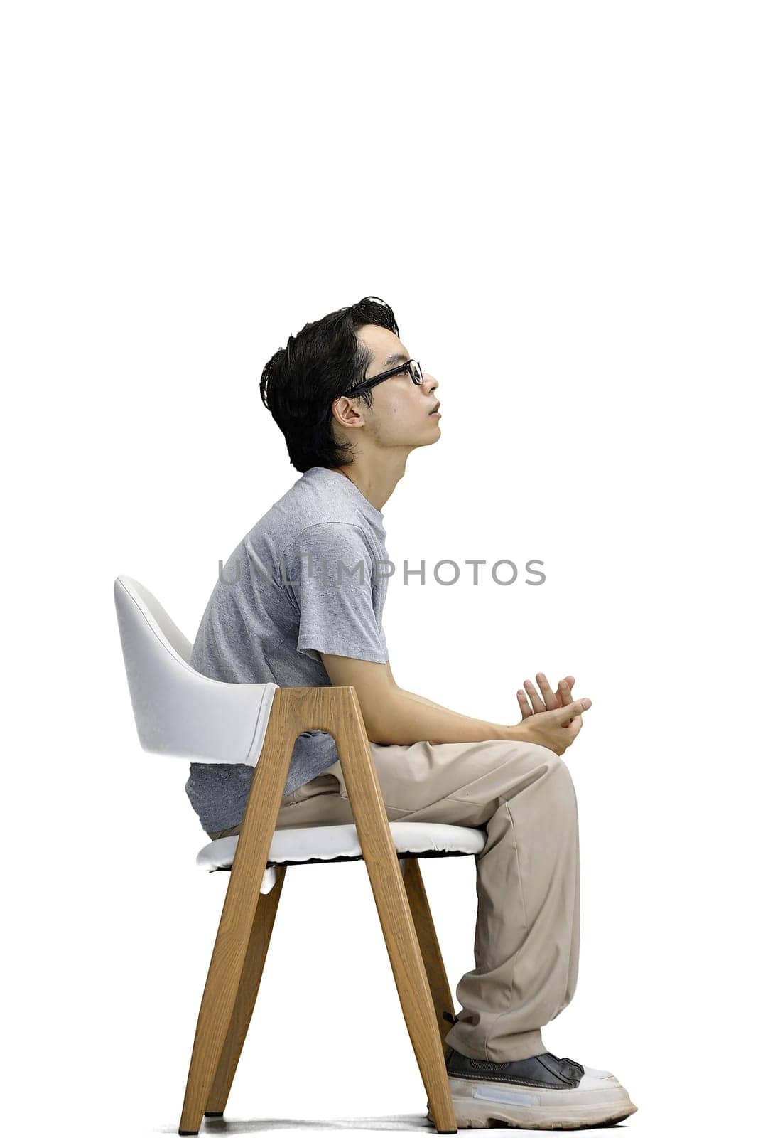 A guy in a gray T-shirt, on a white background, is sitting on a chair by Prosto