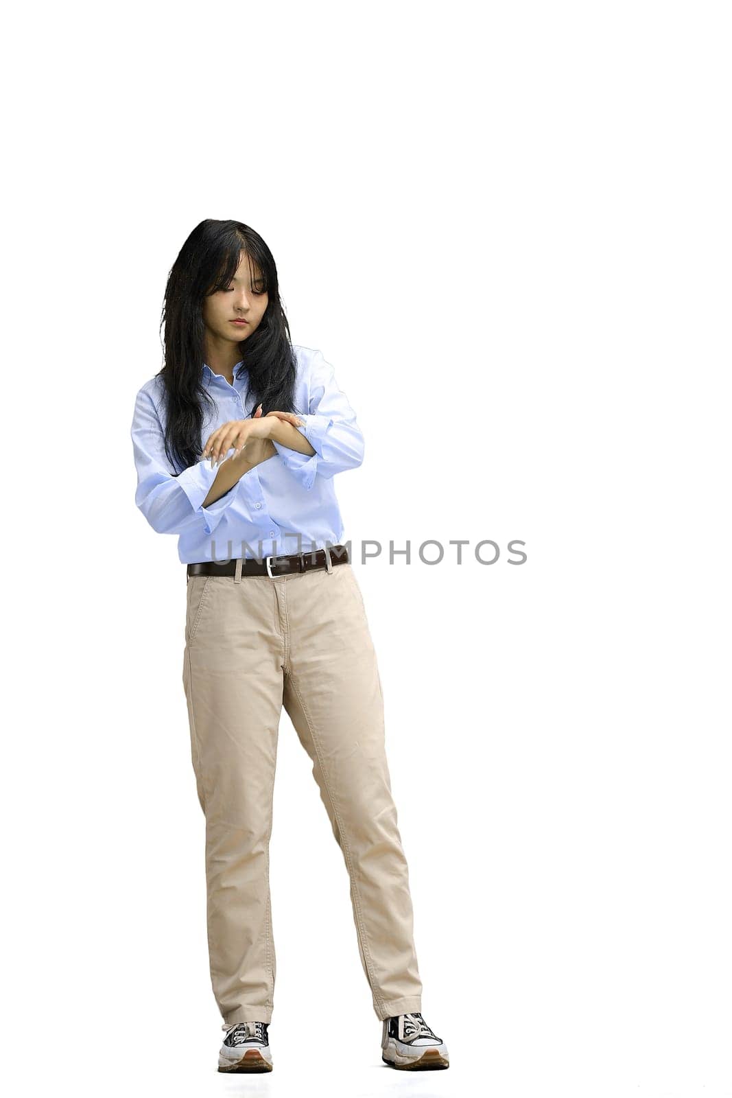 A girl in a blue shirt, on a white background, in full height, looks at the clock by Prosto