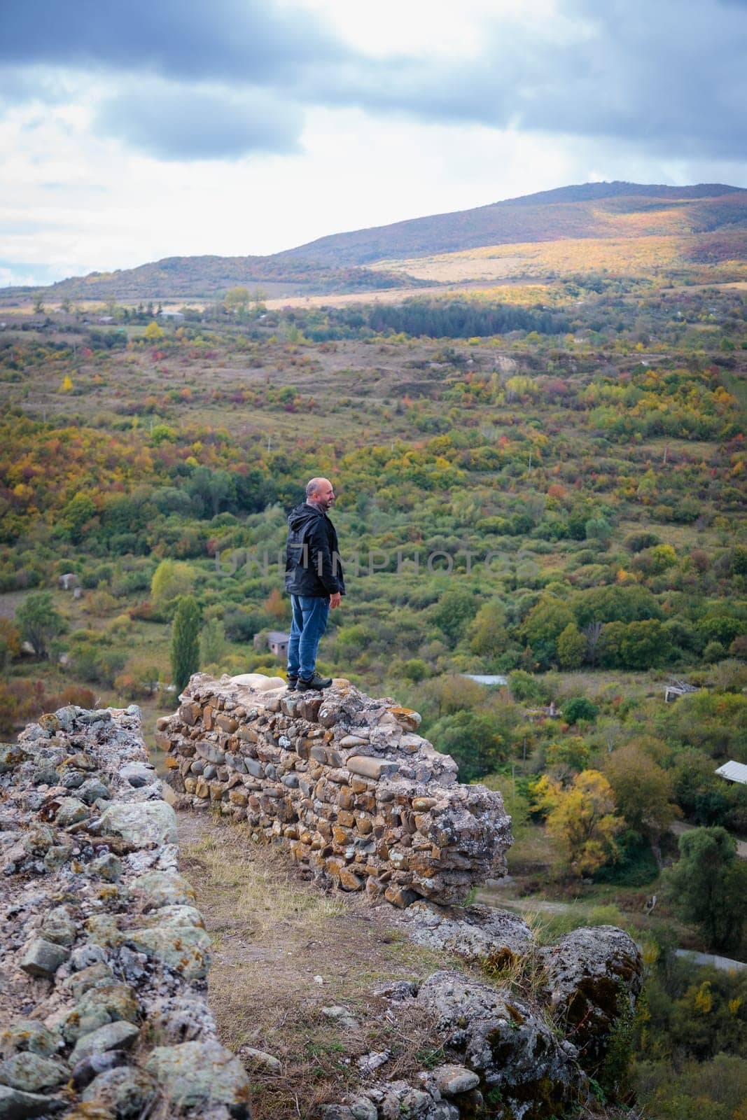 Solitary Moment: Man Standing on Mountain Fortress Ruins, Taking in the Scenery by Yurich32