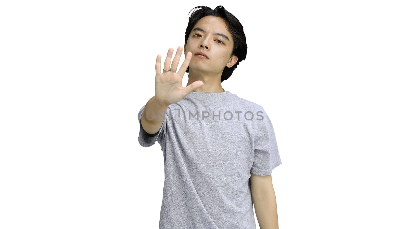 A guy in a gray T-shirt, on a white background, close-up, shows a stop sign.