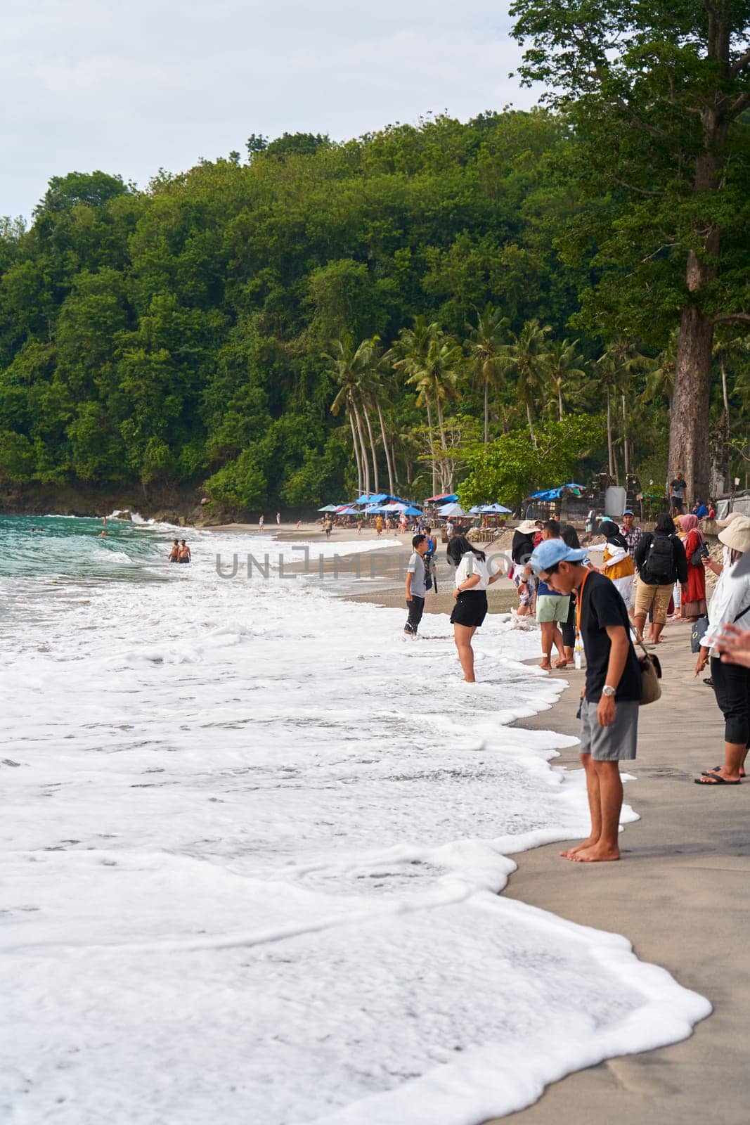 A crowd of tourists walks and takes pictures on a tropical beach. by Try_my_best