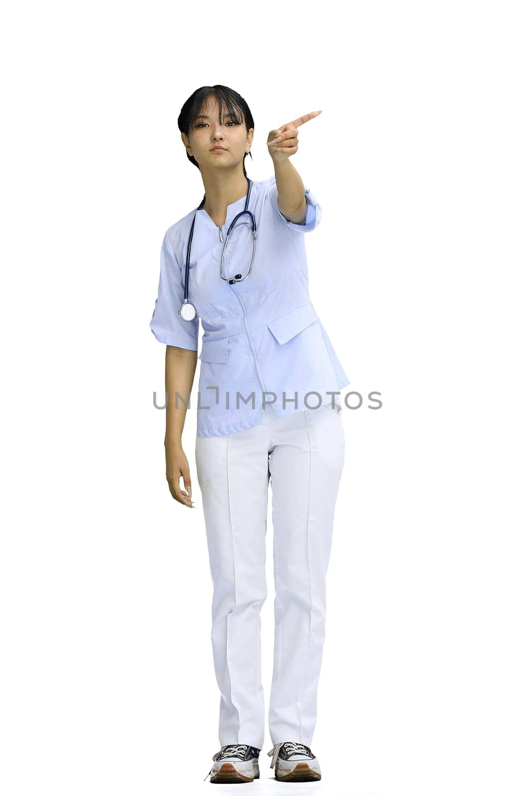 The doctor's girl, on a white background, in full height, points to the side.