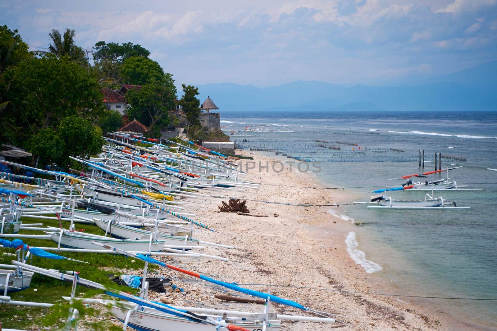 Traditional local colored fisherman's catamaran boats are lined up on the ocean shore on an island in Indonesia