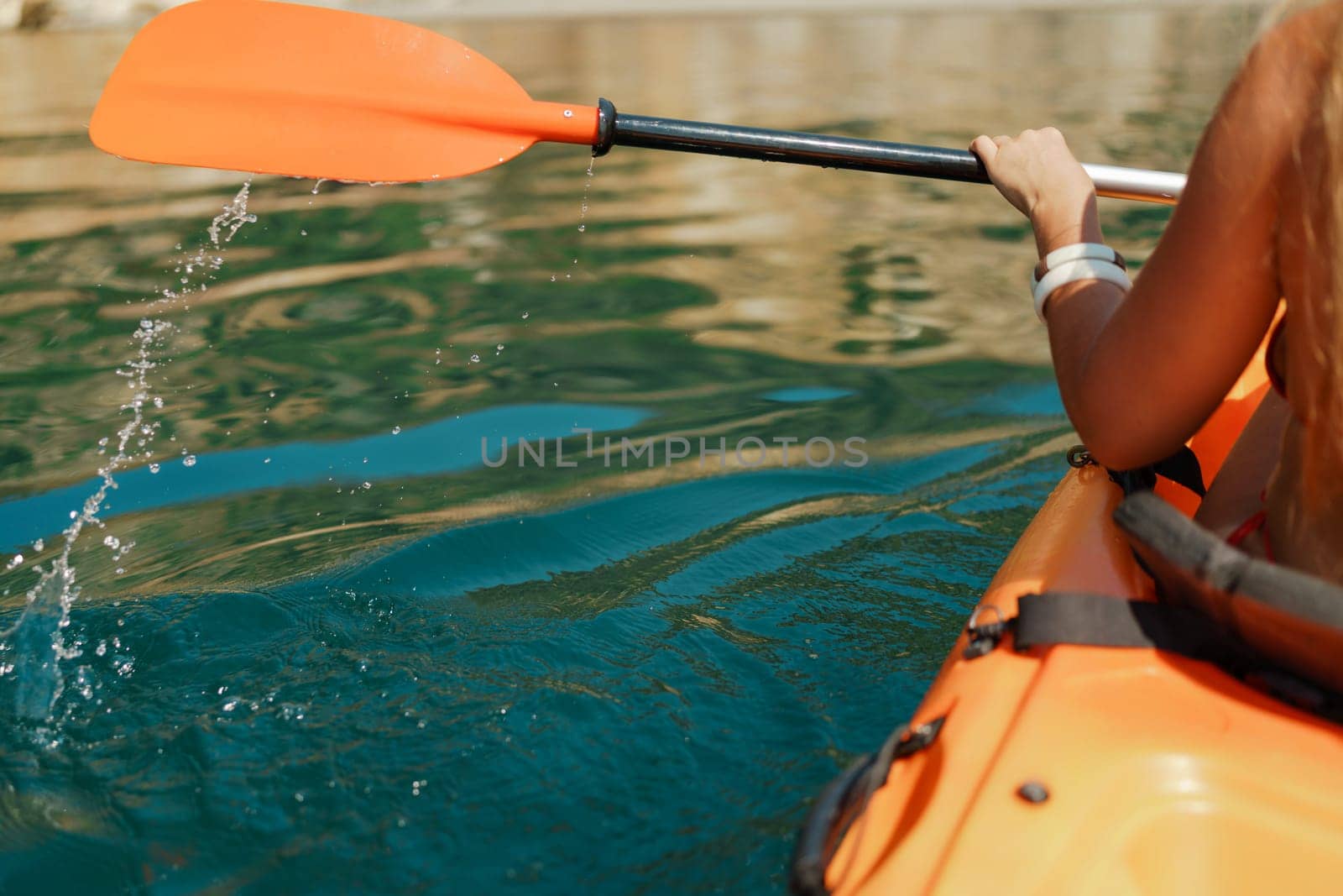 Kayak paddle sea vacation. Person paddles with orange paddle oar on kayak in sea. Leisure active lifestyle recreation activity rest tourism travel.