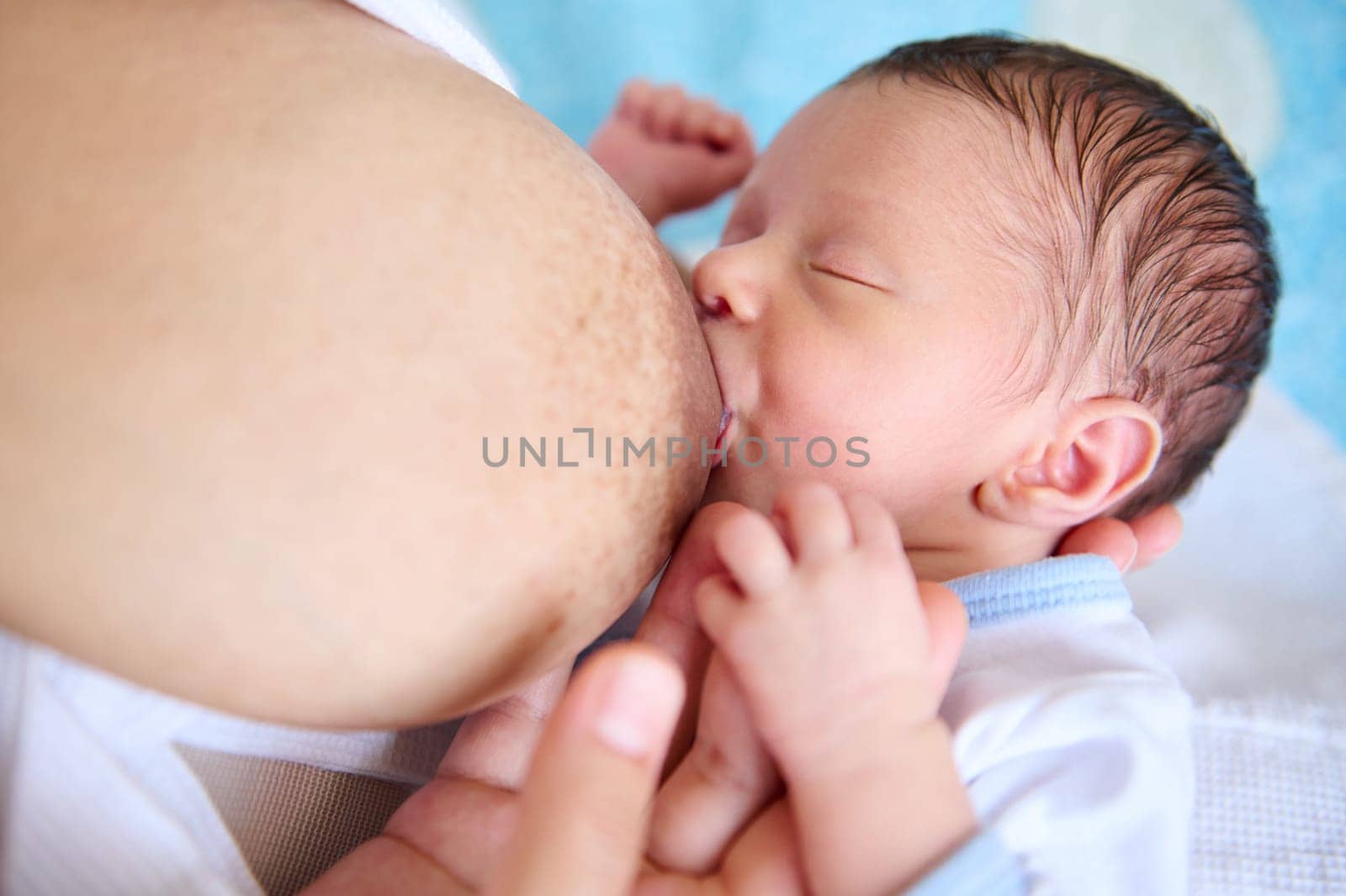 Overhead view of an adorable newborn baby sucking mother's breast. Close-up conscious loving mother breastfeeding her baby. Motherhood. Maternity leave, childhood, people and lifestyle concept