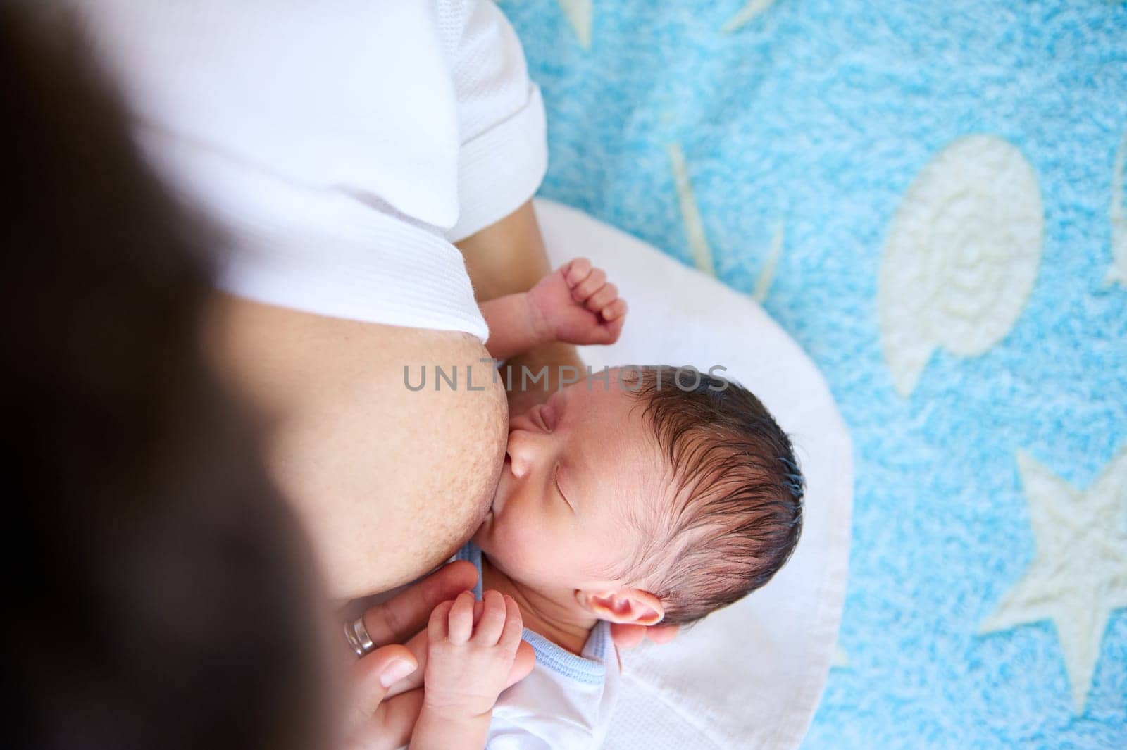 Close-up of Caucasian adorable newborn baby boy suckling the healthy milk from the breast of his mother.. Breastfeeding as one way to reduce the risk and prophylaxis of breast cancer